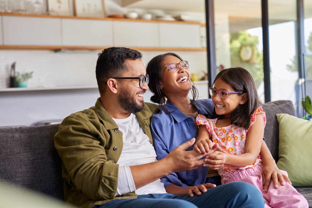 A family laughing together on the couch at home