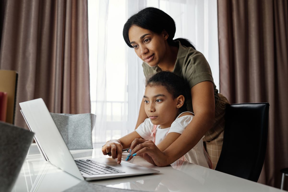 A mother and daughter reviewing information together on a laptop at home